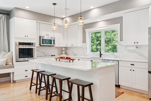 65 Wildbrook Ln, Eliot, ME 03903 - kitchen featuring stainless steel appliances, a breakfast bar, white cabinets, decorative backsplash, and recessed lighting
