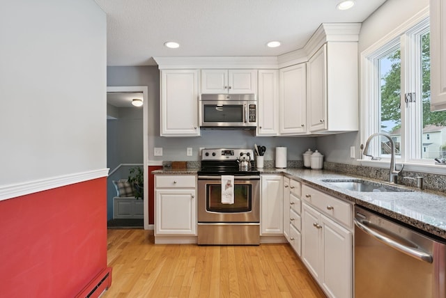 66 Rustic Ln, Portland, ME 04103 - kitchen with stainless steel appliances, white cabinets, stone countertops, light wood-style floors, and recessed lighting