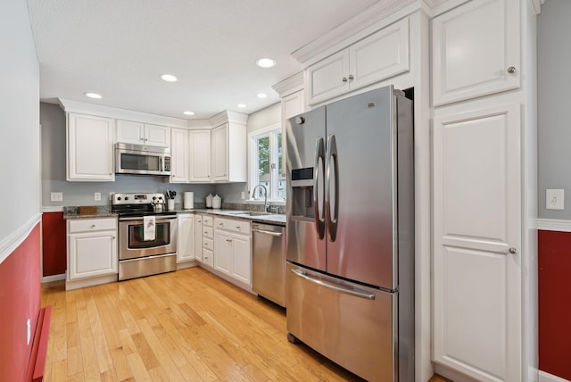 66 Rustic Ln, Portland, ME 04103 - kitchen with stainless steel appliances, white cabinetry, light wood-style floors, recessed lighting, and dark stone countertops