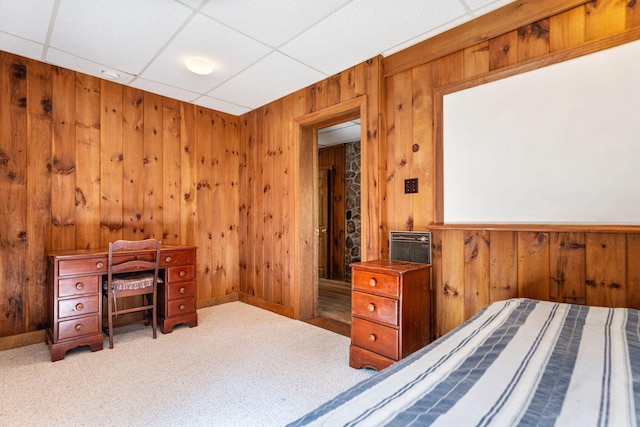carpeted bedroom with wooden walls and a paneled ceiling
