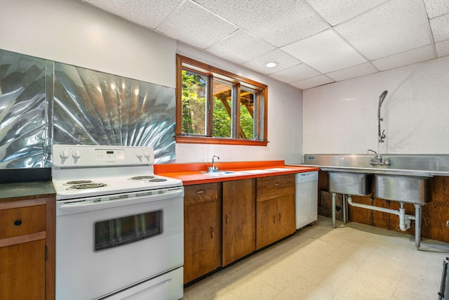 kitchen featuring white appliances, light floors, brown cabinetry, a paneled ceiling, and light countertops