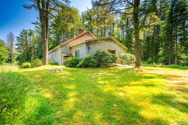 view of side of home with a lawn and a chimney