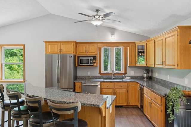 2288 W River Rd, Sidney, ME 04330 - kitchen with stainless steel appliances, vaulted ceiling, ceiling fan, a breakfast bar area, and wood finished floors