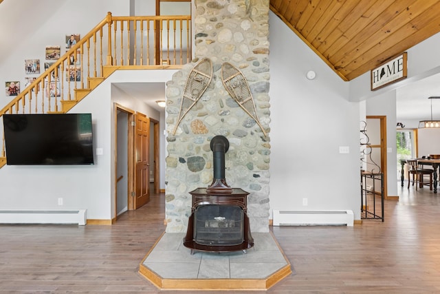 2288 W River Rd, Sidney, ME 04330 - living area with a baseboard radiator, high vaulted ceiling, wood finished floors, a wood stove, and wood ceiling
