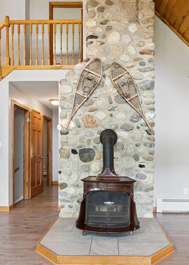 2288 W River Rd, Sidney, ME 04330 - detailed view of a baseboard heating unit, a wood stove, and wood finished floors