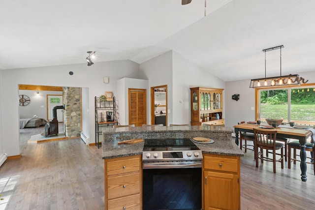 2288 W River Rd, Sidney, ME 04330 - kitchen featuring stainless steel electric range oven, lofted ceiling, light wood-type flooring, a wood stove, and a center island