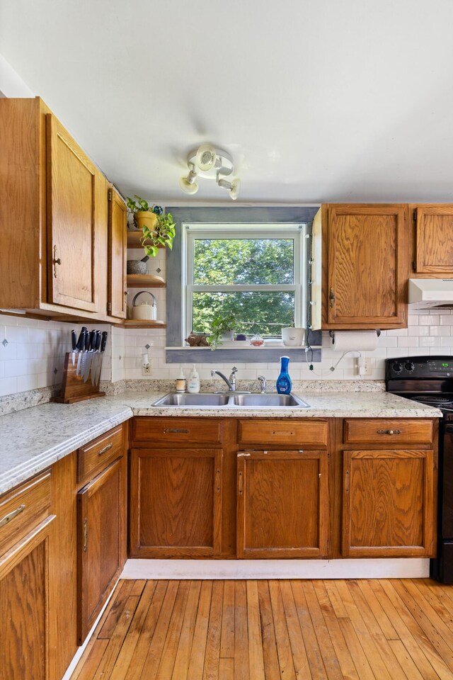 46 Meadow Way, Bath, ME 04530 - kitchen with black electric range, decorative backsplash, under cabinet range hood, and brown cabinetry