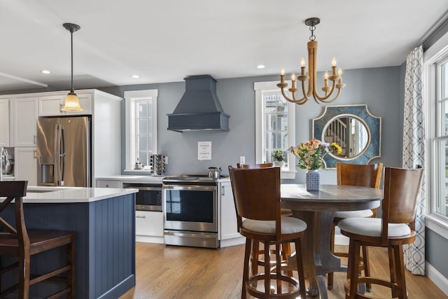 38 Atlantic Ave, Boothbay Harbor, ME 04538 - kitchen featuring appliances with stainless steel finishes, premium range hood, wood finished floors, white cabinetry, and a chandelier