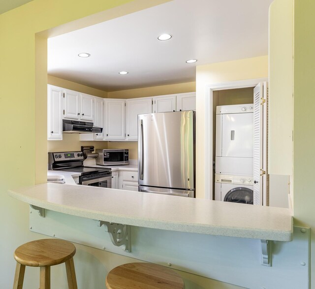 3 Curtis Ave, Camden, ME 04843 - kitchen with stainless steel appliances, stacked washer / drying machine, ventilation hood, light countertops, and white cabinetry