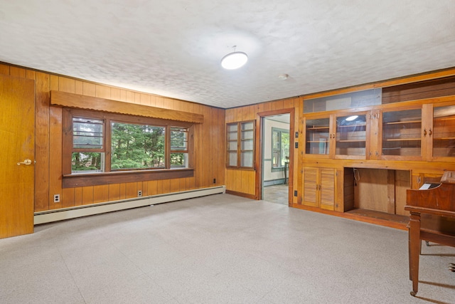 219 Mouse Ln, Alfred, ME 04002 - unfurnished living room with baseboard heating, wooden walls, a textured ceiling, and a baseboard heating unit