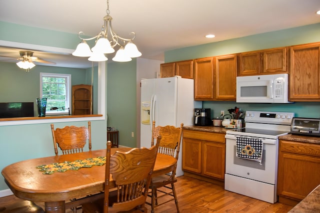15 Good Heart Ln, Orrington, ME 04474 - kitchen with white appliances, brown cabinets, light wood-type flooring, a chandelier, and dark countertops