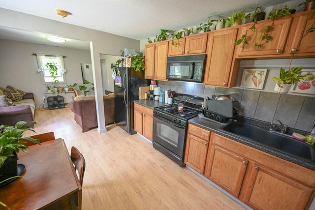 488 Bog Rd, Hermon, ME 04401 - kitchen with black appliances, light wood-style floors, backsplash, dark countertops, and open floor plan