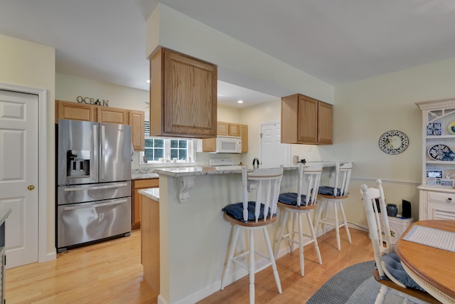 23 Chestnut Ln Unit 23, Wells, ME 04090 - kitchen featuring stainless steel refrigerator with ice dispenser, light wood-style flooring, a peninsula, a kitchen bar, and recessed lighting