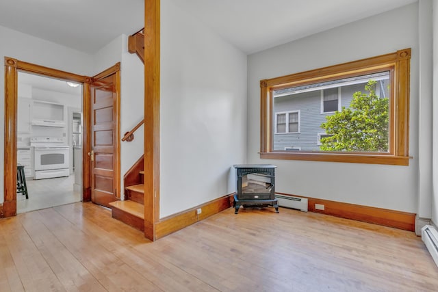 15 Snow Park, Bath, ME 04530 - empty room featuring a wood stove, a baseboard heating unit, wood finished floors, and a baseboard radiator