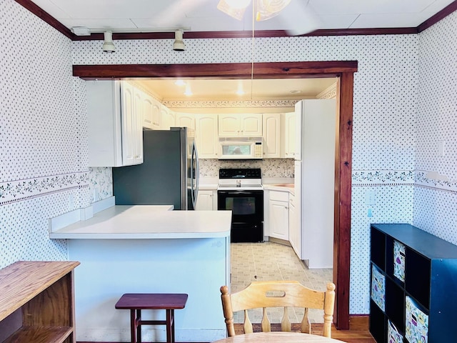 17 Pleasant St, Wilton, ME 04294 - kitchen featuring freestanding refrigerator, white microwave, range with electric cooktop, wallpapered walls, and a peninsula