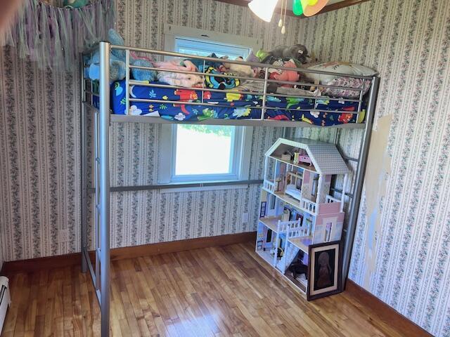 17 Pleasant St, Wilton, ME 04294 - bedroom with wallpapered walls, wood finished floors, and a baseboard heating unit