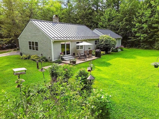 1 Castle View Ln, Belgrade, ME 04917 - rear view of house featuring a standing seam roof, a chimney, a metal roof, a patio, and a yard