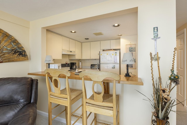 191 E Grand Ave Unit 504, Old Orchard Beach, ME 04064 - kitchen with freestanding refrigerator, a kitchen bar, under cabinet range hood, a peninsula, and recessed lighting