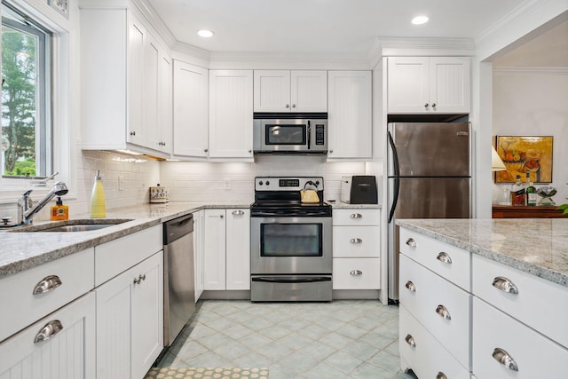 239 Sea Rd Unit 32, Kennebunk, ME 04043 - kitchen with appliances with stainless steel finishes, white cabinets, tasteful backsplash, crown molding, and light stone countertops