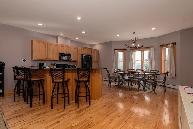 7022 Hardwood Ridge Rd Unit 7022, Carrabassett Valley, ME 04947 - kitchen with black appliances, light wood-style floors, a chandelier, recessed lighting, and dark countertops