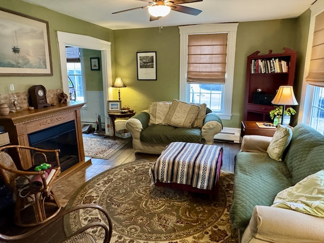 21 Wilson St, Eastport, ME 04631 - living area featuring ceiling fan, a baseboard radiator, plenty of natural light, and a glass covered fireplace