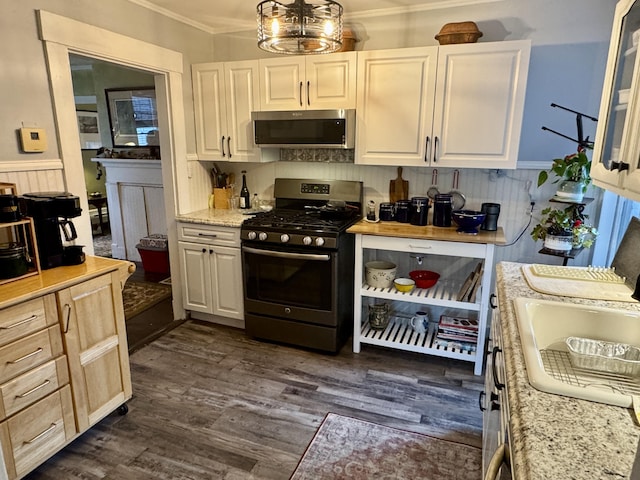 21 Wilson St, Eastport, ME 04631 - kitchen featuring stainless steel appliances, crown molding, dark wood-style flooring, white cabinets, and wainscoting