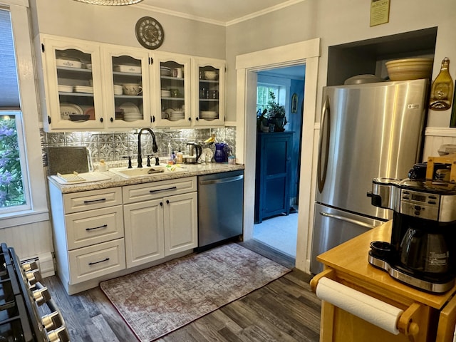 21 Wilson St, Eastport, ME 04631 - kitchen with appliances with stainless steel finishes, decorative backsplash, ornamental molding, glass insert cabinets, and white cabinetry