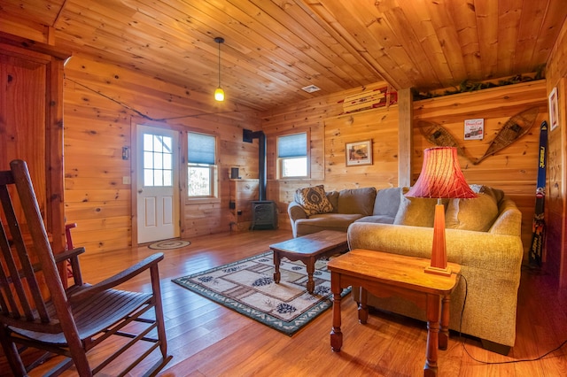 49 Winston Rd, Rangeley, ME 04970 - living area with a wood stove, wooden walls, healthy amount of natural light, light wood-style flooring, and wooden ceiling