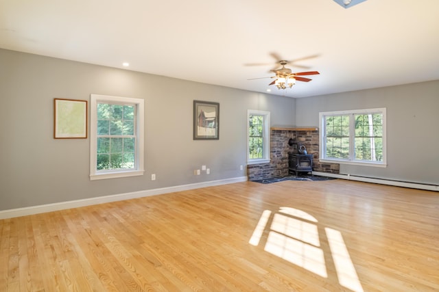 34 Perk Orock Landing Rd, Orono, ME 04473 - unfurnished living room with a wood stove, light wood finished floors, ceiling fan, and a baseboard radiator