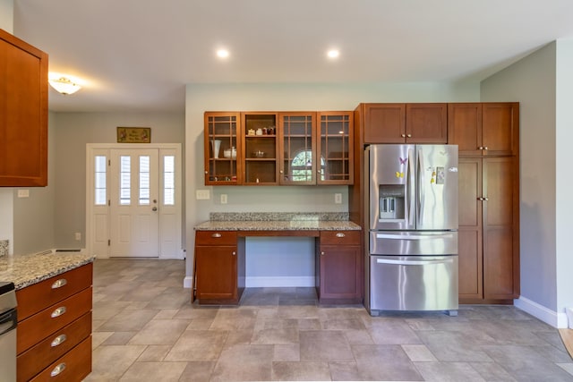 34 Perk Orock Landing Rd, Orono, ME 04473 - kitchen featuring stainless steel refrigerator with ice dispenser, glass insert cabinets, light stone countertops, brown cabinets, and stone finish flooring
