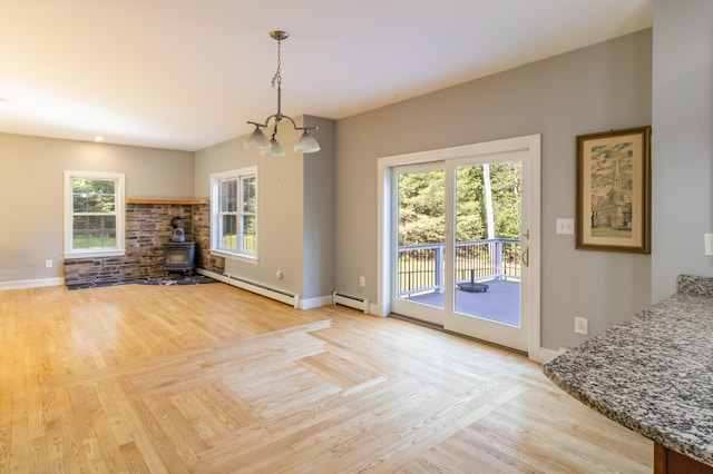 34 Perk Orock Landing Rd, Orono, ME 04473 - unfurnished living room with a wood stove, a chandelier, a baseboard heating unit, and light wood-style floors
