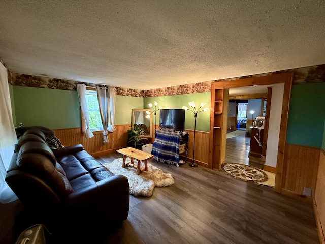 1897 Pequawket Trl, Hiram, ME 04041 - living area featuring a textured ceiling, wainscoting, wood walls, wood finished floors, and plenty of natural light