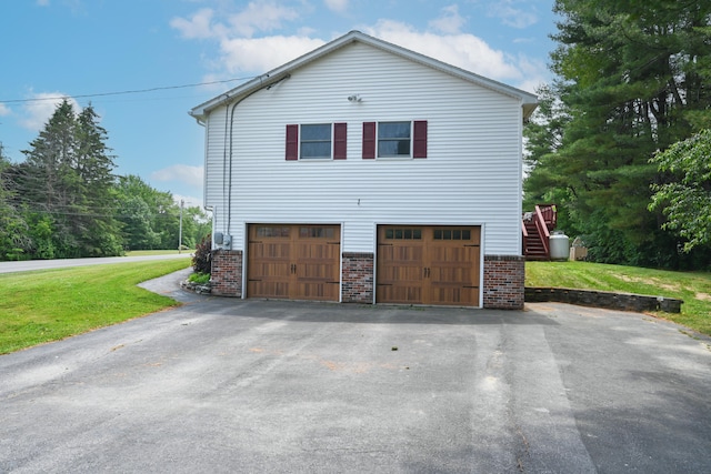 13 Evergreen Dr, Hampden, ME 04444 - view of side of property featuring brick siding, a yard, asphalt driveway, and an attached garage