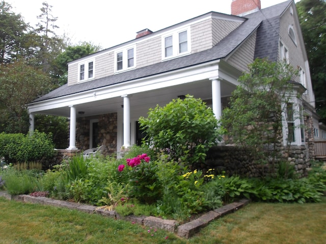 18 Wayman Ln, Bar Harbor, ME 04609 - view of front of house with a chimney, a shingled roof, covered porch, and stone siding