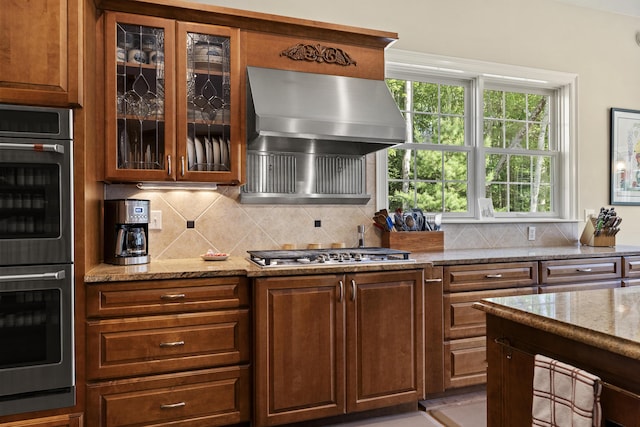 28 Evergreen Dr, Boothbay, ME 04537 - kitchen with stainless steel appliances, exhaust hood, backsplash, light stone counters, and glass insert cabinets