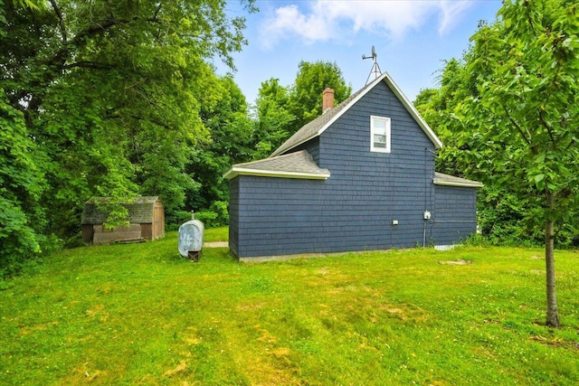 90 Newbury St, Auburn, ME 04210 - view of home's exterior with a yard, a chimney, a storage unit, and roof with shingles