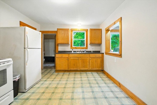 90 Newbury St, Auburn, ME 04210 - kitchen with dark countertops, white appliances, brown cabinetry, and light floors