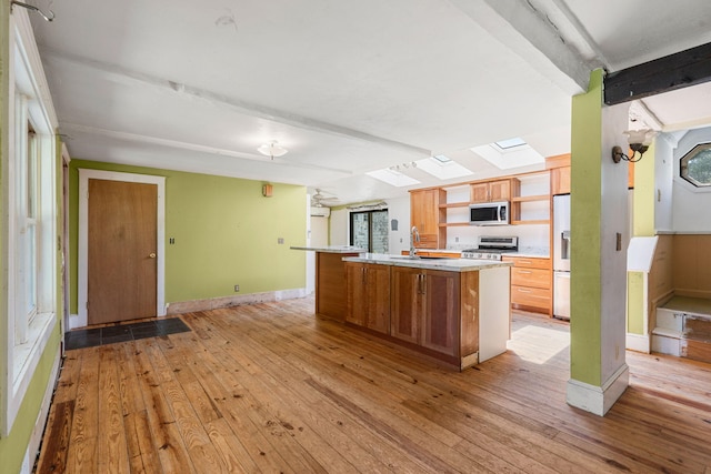 276 W St, Biddeford, ME 04005 - kitchen with range, a skylight, stainless steel microwave, and light wood finished floors