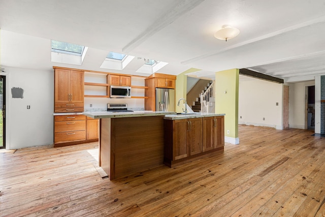 276 W St, Biddeford, ME 04005 - kitchen featuring appliances with stainless steel finishes, open shelves, a skylight, and light wood-style flooring
