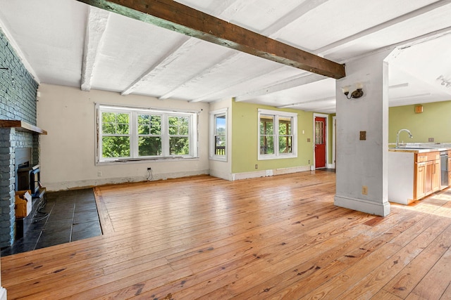 276 W St, Biddeford, ME 04005 - unfurnished living room with light wood-type flooring, healthy amount of natural light, a fireplace, and beamed ceiling