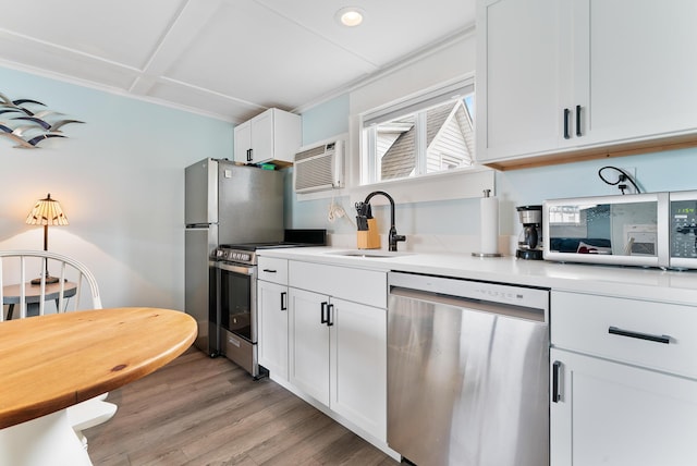 7 Bay Ave Unit 11, Old Orchard Beach, ME 04064 - kitchen featuring appliances with stainless steel finishes, an AC wall unit, light countertops, white cabinetry, and light wood-style flooring