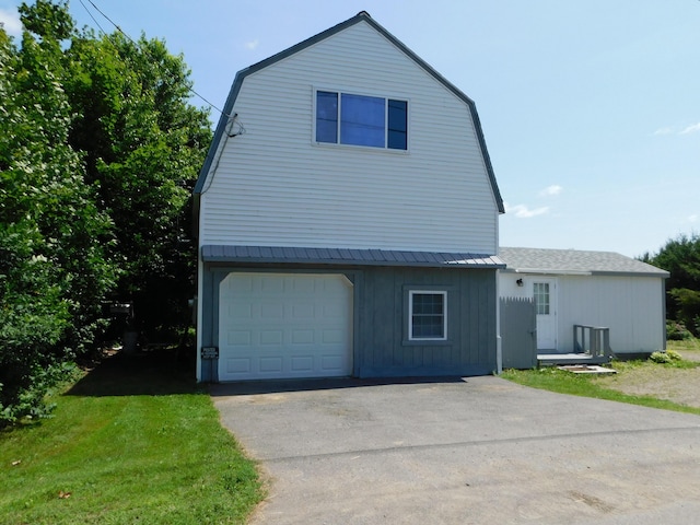 208 Fern Rd, Dexter, ME 04930 - colonial inspired home with a gambrel roof, a garage, asphalt driveway, and board and batten siding