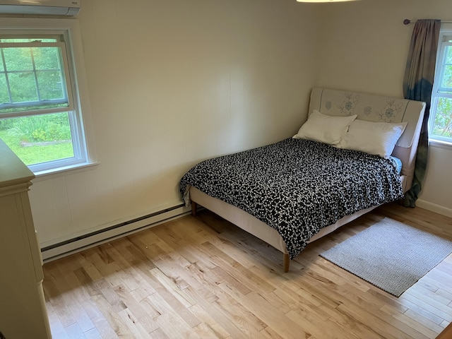 363 Oak Point Rd, Trenton, ME 04605 - bedroom featuring light wood-style floors, multiple windows, a baseboard heating unit, and an AC wall unit