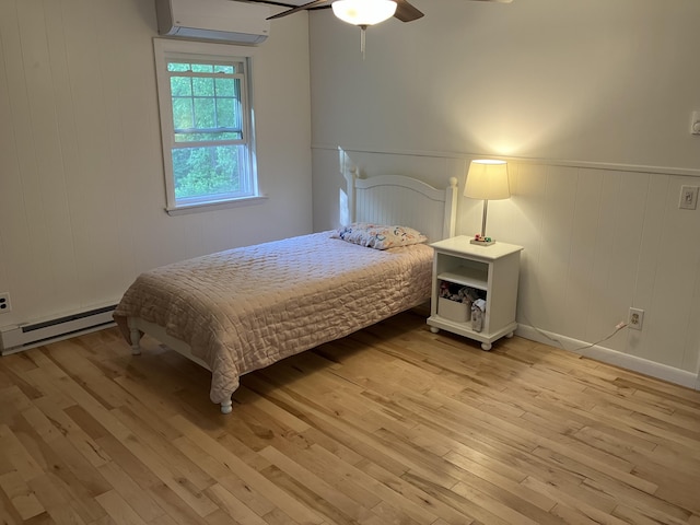 363 Oak Point Rd, Trenton, ME 04605 - bedroom with baseboard heating, a wall mounted AC, light wood-style floors, a wainscoted wall, and a ceiling fan