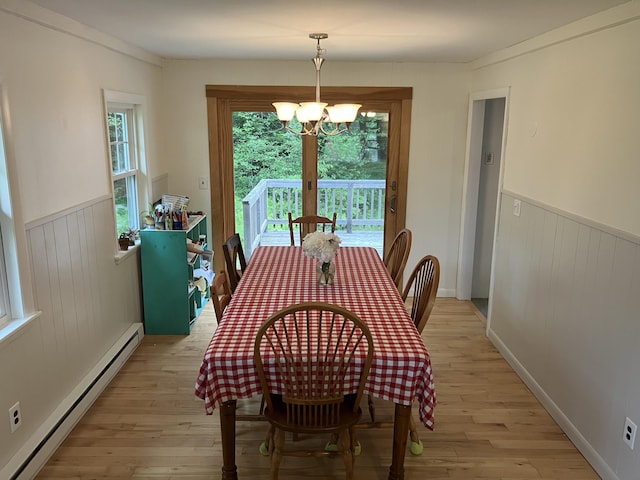 363 Oak Point Rd, Trenton, ME 04605 - dining room with a baseboard radiator, light wood finished floors, wainscoting, a chandelier, and wood walls