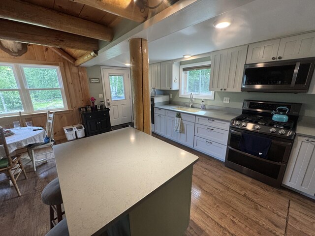 71 Garland Rd, Dixmont, ME 04932 - kitchen with appliances with stainless steel finishes, dark wood finished floors, light countertops, a kitchen breakfast bar, and wooden walls