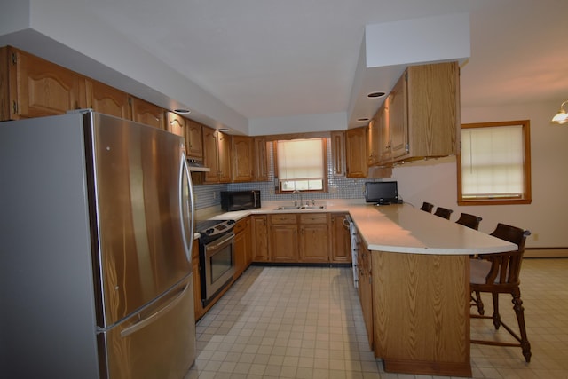 94 Blaisdell Rd, Newport, ME 04953 - kitchen with appliances with stainless steel finishes, a peninsula, a kitchen breakfast bar, under cabinet range hood, and light countertops