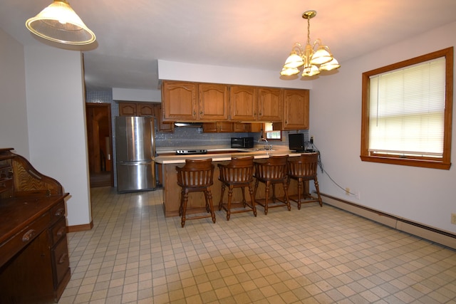 94 Blaisdell Rd, Newport, ME 04953 - kitchen with freestanding refrigerator, a chandelier, backsplash, brown cabinets, and a peninsula