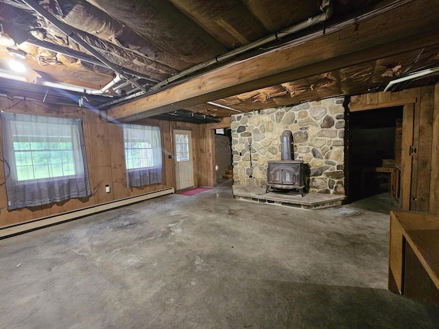 94 Blaisdell Rd, Newport, ME 04953 - basement featuring a wood stove, a baseboard heating unit, and wooden walls