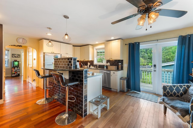 736 Webster St, Lewiston, ME 04240 - kitchen with stainless steel dishwasher, a breakfast bar area, arched walkways, hardwood / wood-style floors, and dark countertops